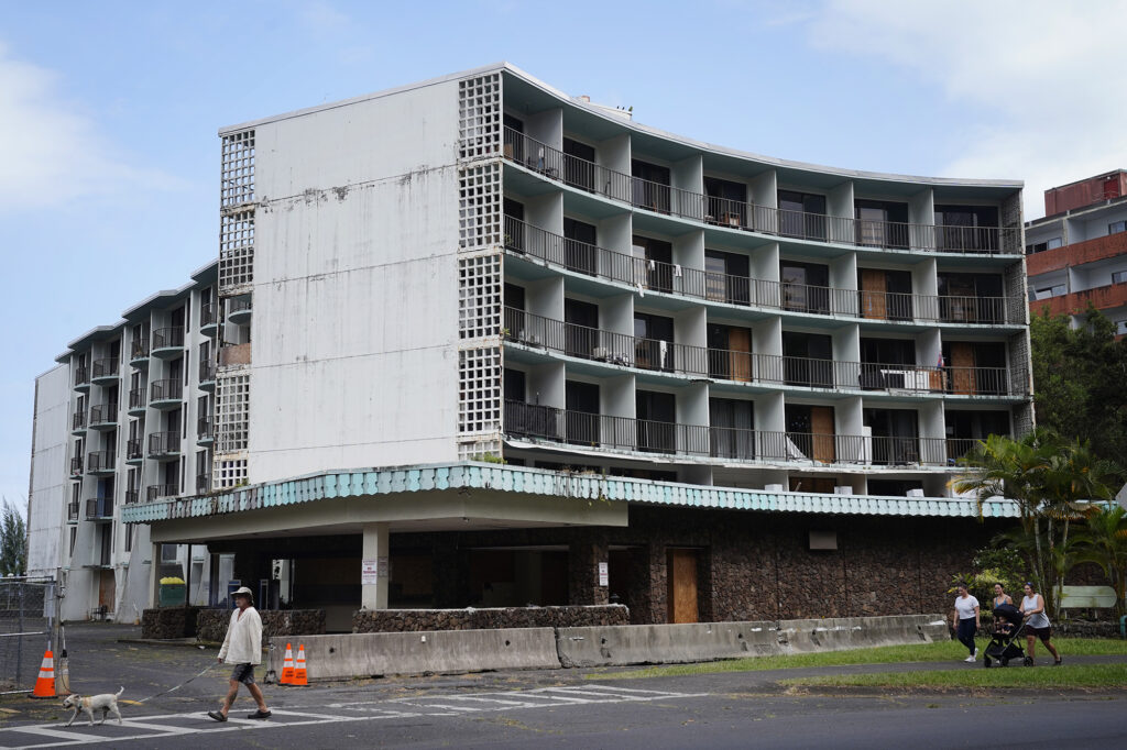Pedestrians walk along Banyan Drive in front of the dilapidated Country Club Condominium Thursday, Feb. 5, 2026, in Hilo. State legislators are pushing to revitalize this once bustling area. (Kevin Fujii/Civil Beat/2026)