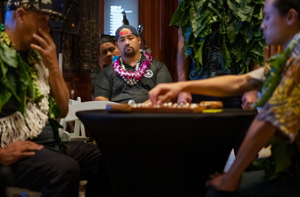 Akua Boards craftsman Wallace Akua, center, watches Kahekili Yung, right, of Oʻahu, make a move against Kauaʻi’s Kimo Chun, left, during the semifinals of the inaugural Ka Makou Kōnane Invitational Tournament takes place at the Bishop Museum Friday, Feb. 13, 2026, in Honolulu. (Kevin Fujii/Civil Beat/2026)