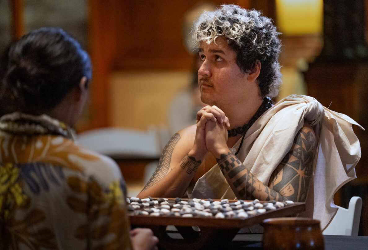 Kapena Baptista, looks up to ki‘i Kanaloa while playing Kahekili Yung, right, during the championship match of the inaugural Ka Makou Kōnane Invitational Tournament in the center of the Bishop Museum’s Hawaiʻian Hall Friday, Feb. 13, 2026, in Honolulu. (Kevin Fujii/Civil Beat/2026)
