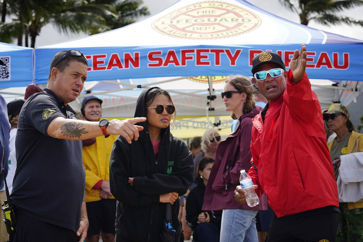Kaua‘i Ocean Safety Bureau Lt. Kleve Zarbaugh, left, and Operation Chief Kalani Vierra, right, point out the the rip current off Waiʻoli Beach Park to Envy Naluz during Hawaiʻi’s first rip-current clinic Wednesday, Feb. 18, 2026, in Hanalei. (Kevin Fujii/Civil Beat/2026)