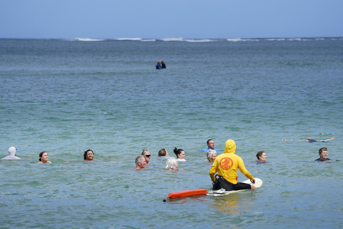 Ocean safety educator Bruce “Hoppo” Hopkins of Australia, center wearing blue rashguard, instructs rip-current clinic participants to look at the shore to see how far the rip current moved them at Waiʻoli Beach Park Wednesday, Feb. 18, 2026, in Hanalei. This rip current debunks the previous belief to swim parallel to shore if a rip moves you from your starting point. Hopkins stresses floating instead of swimming. By floating, the swimmer saves valuable energy and allows the current to move them to a safer place where they can self rescue or make rescue by a lifeguard safer. (Kevin Fujii/Civil Beat/2026)