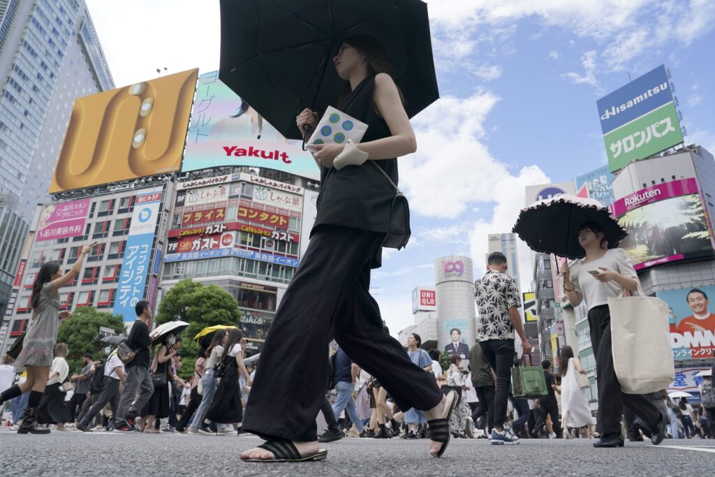 People walk along Shibuya scramble crossing under hot and sunny weather, Wednesday, Aug. 28, 2024, in Tokyo. (AP Photo/Eugene Hoshiko)