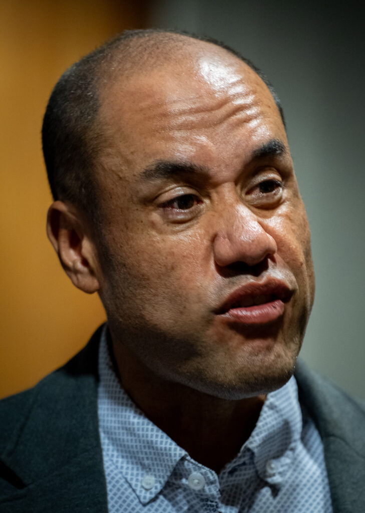 A man with closely cropped hair, thinning on top, wrinkles his face in this tight portrait.