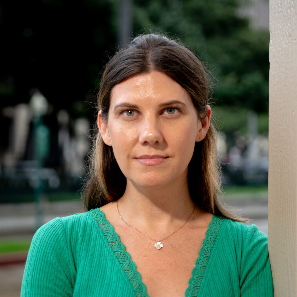 A portrait of a woman with long brown hair wearing a green top.