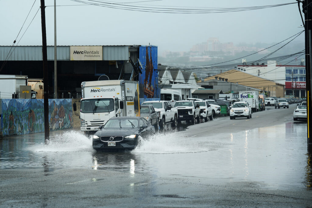 A car drives through standing water in Mapunapuna as a Kona Low storm arrives on O‘ahu Thursday, March 19, 2026, in Honolulu. (Kevin Fujii/Civil Beat/2026)