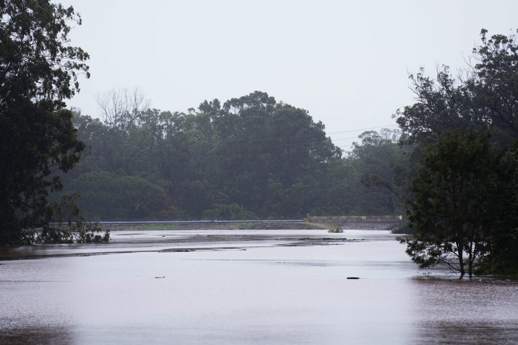 A person looks over the Wahiawā Reservoir dam as rain from the second Kona Low raises the level of Lake Wilson Friday, March 20, 2026, in Wahiawā. (Kevin Fujii/Civil Beat/2026)