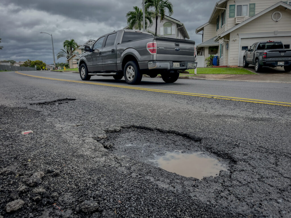 A truck drives past potholes that formed during the recent heavy rains on Lumiaina St in Waipahu, March 21, 2026. (Craig Fujii/Civil Beat/2026)