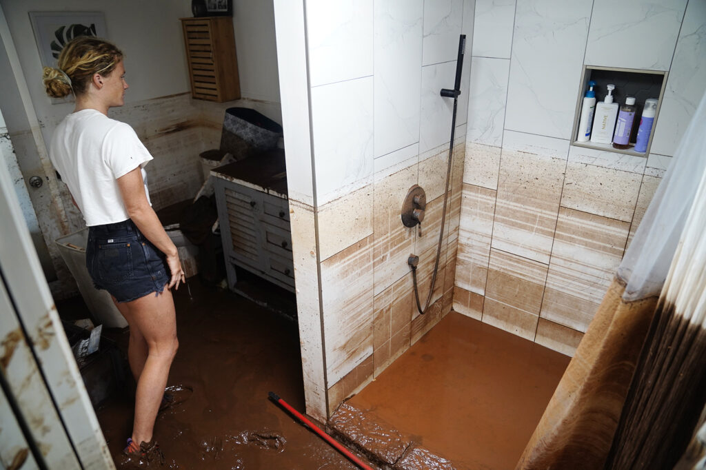 “Well, my shampoo is still good,” India Myercough says lightheartedly (808-780-0810) as she checks out her bathroom Saturday, March 21, 2026, in Waialua. Myercough was flooded by both Kona Low storms. (Kevin Fujii/Civil Beat/2026)