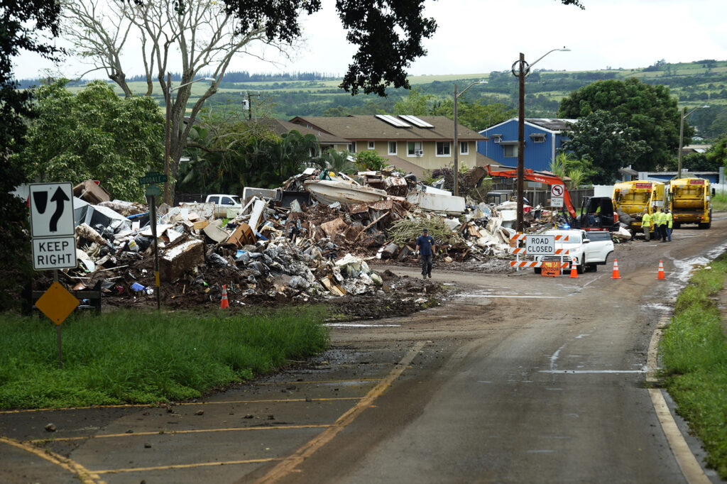 Rubbish is piled into the middle of the traffic circle Monday, March 23, 2026, in Waialua. The traffic circle has become a make-shift refuse transfer center for nearby homes affected by the Kona Storm flooding. (Kevin Fujii/Civil Beat/2026)
