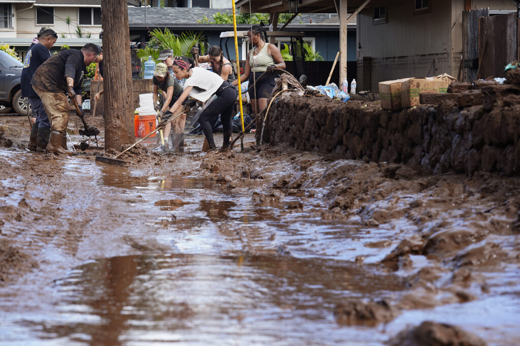 Volunteers push out mud at a Haona Street home Monday, March 23, 2026, in Waialua. A second Kona low storm brought heavy rain after the previous week’s downpour and high winds. (Kevin Fujii/Civil Beat/2026)
