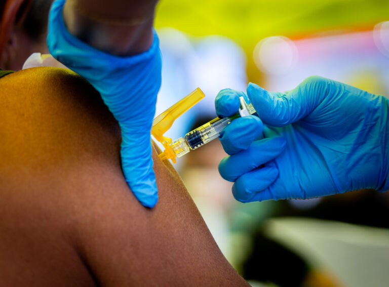 A patient with open wounds and a skin infection receives a tetanus vaccination March 26, 2026. He was seen at a mobile clinic set up by student doctors at John A. Burns School of Medicine at Ali'i Beach Park in Haleiwa for local residents affected by the Kona Low storm.  (Craig Fujii/Civil Beat/2026)