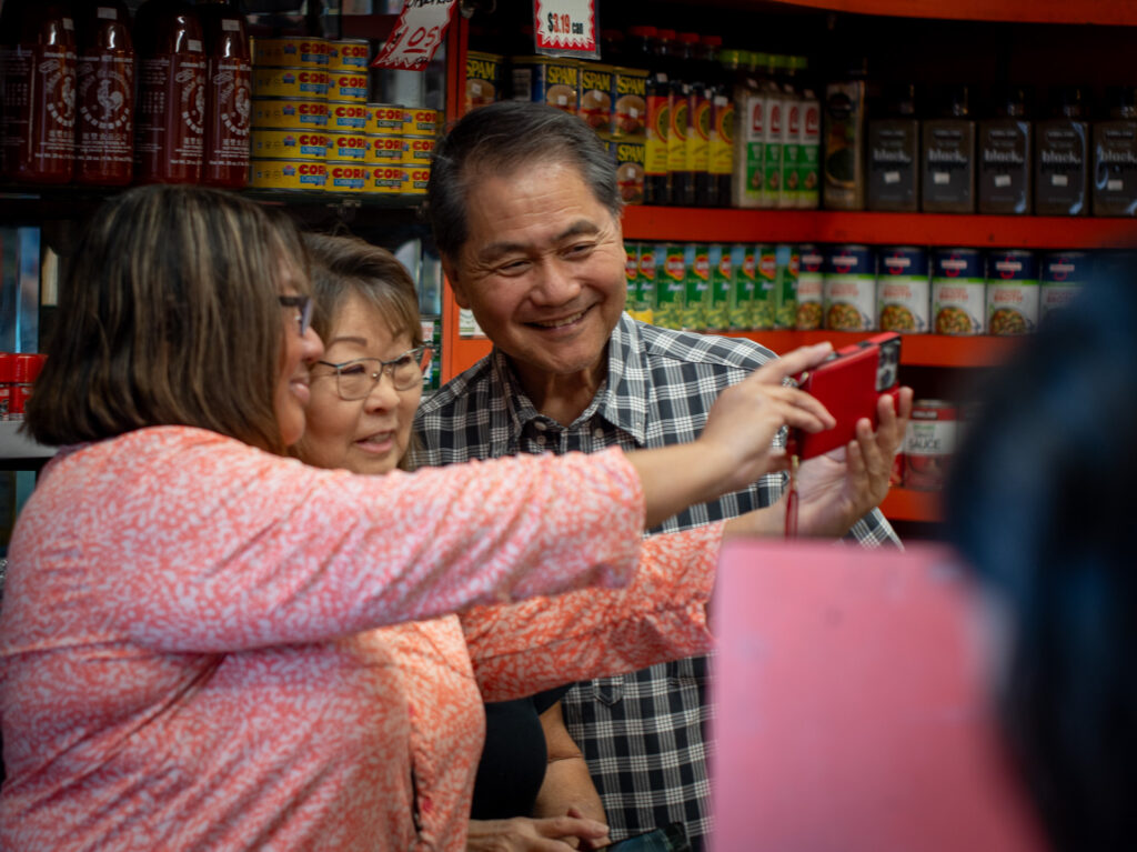 Grace Rabor, left, takes a selfie with Colleen Edal and Cyrus Tamashiro at Tamashiro Market April 3, 2026. Rabor has worked at the family market for 49 years. The market closes April 30th. (Craig Fujii/Civil Beat/2026)
