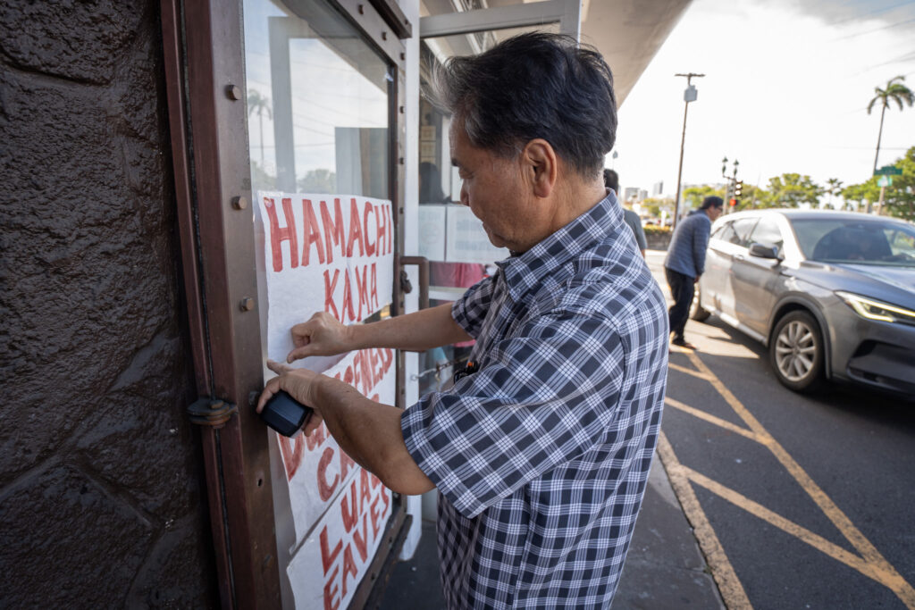 Cyrus Tamashiro puts up hand-painted signs daily at Tamashiro Market showing the current stock of fresh fish April 3, 2026. The 85-year-old institution will close April 30th.