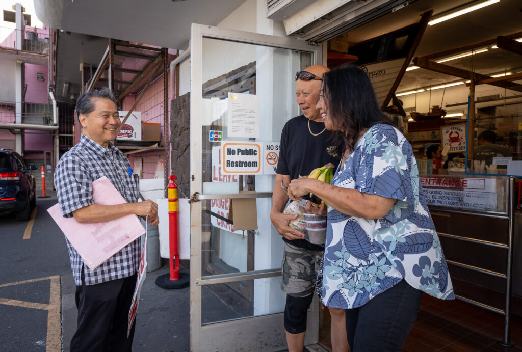 Cyrus Tamashiro, left, is greeted by long-time market customers Ben and Rena Wong at Tamashiro Market April 3, 2026. The store closes April 30th, after being open for 85 years.