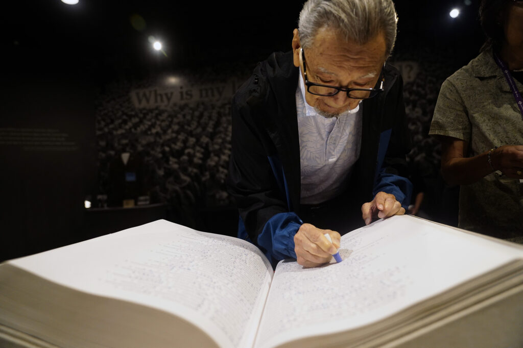 Kazuo Fujii stamps a relative’s name in the Ireichō Thursday, April 9, 2026, at the Japanese Culture Center of Hawaiʻi in Honolulu. The book monument contains 125,284 names of individuals of Japanese ancestry incarcerated during World War II. The Ireichō stops in Honolulu for four days on its national tour. (Kevin Fujii/Civil Beat/2026)