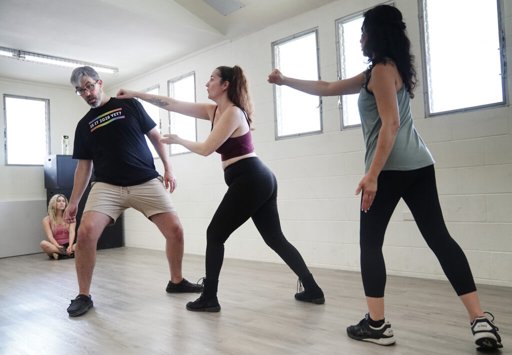 Jasmine Haley Anderson, center, shows students Stephanie Duarte, right, and Miriam Yasdanpanahi, left, how to punch teaching assistant Andrew Simmons during an unarmed stage combat class Saturday, April 11, 2026, at Manoa Valley Theatre in Honolulu. Anderson is a certified instructor through Dueling Arts International. (Kevin Fujii/Civil Beat/2026)