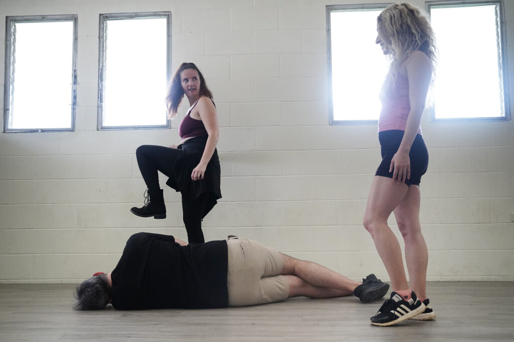 Certified unarmed stage combat instructor Jasmine Haley Anderson, upper left, talks through a scene with student Miriam Yazdanpanahi, standing right, with teaching assistant Andrew Simmons on the receiving end of the action Saturday, April 11, 2026, at Manoa Valley Theatre in Honolulu. Anderson teaches through Dueling Arts International. (Kevin Fujii/Civil Beat/2026)