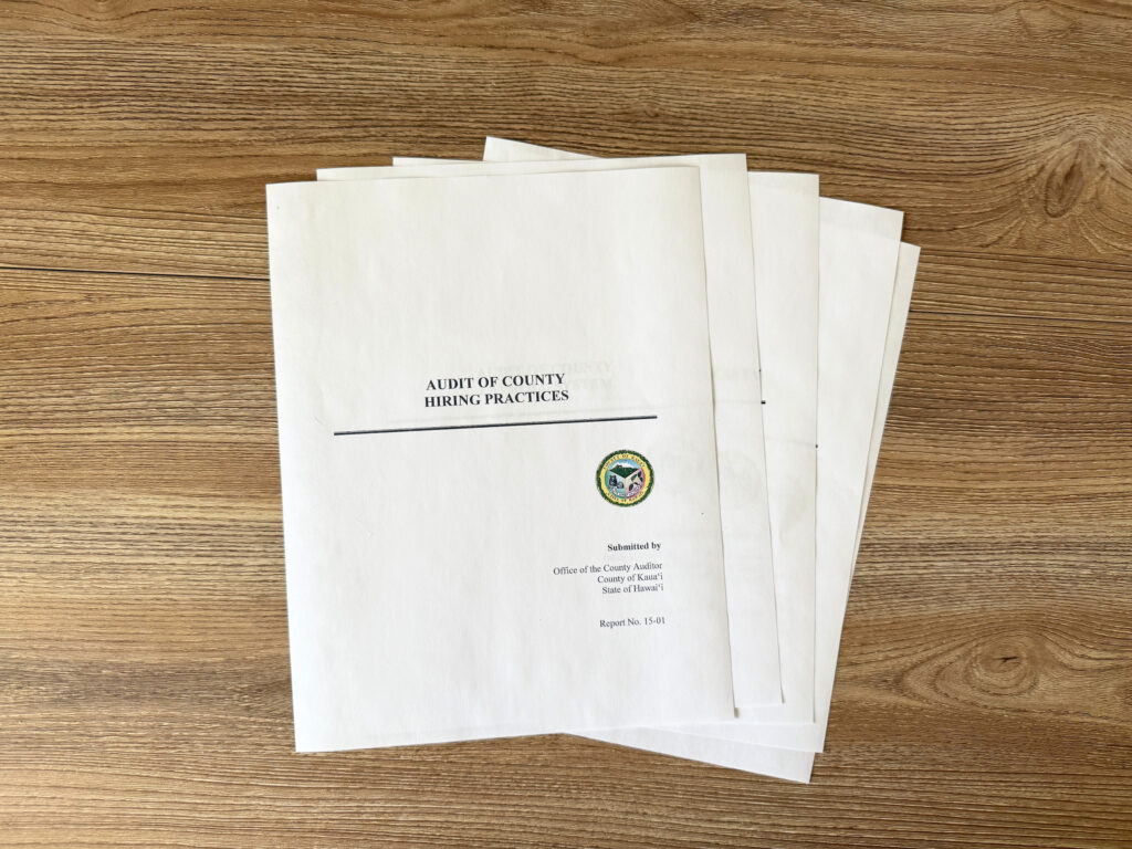 A stack of papers with "Audit of County Hiring Practices" on the first page.