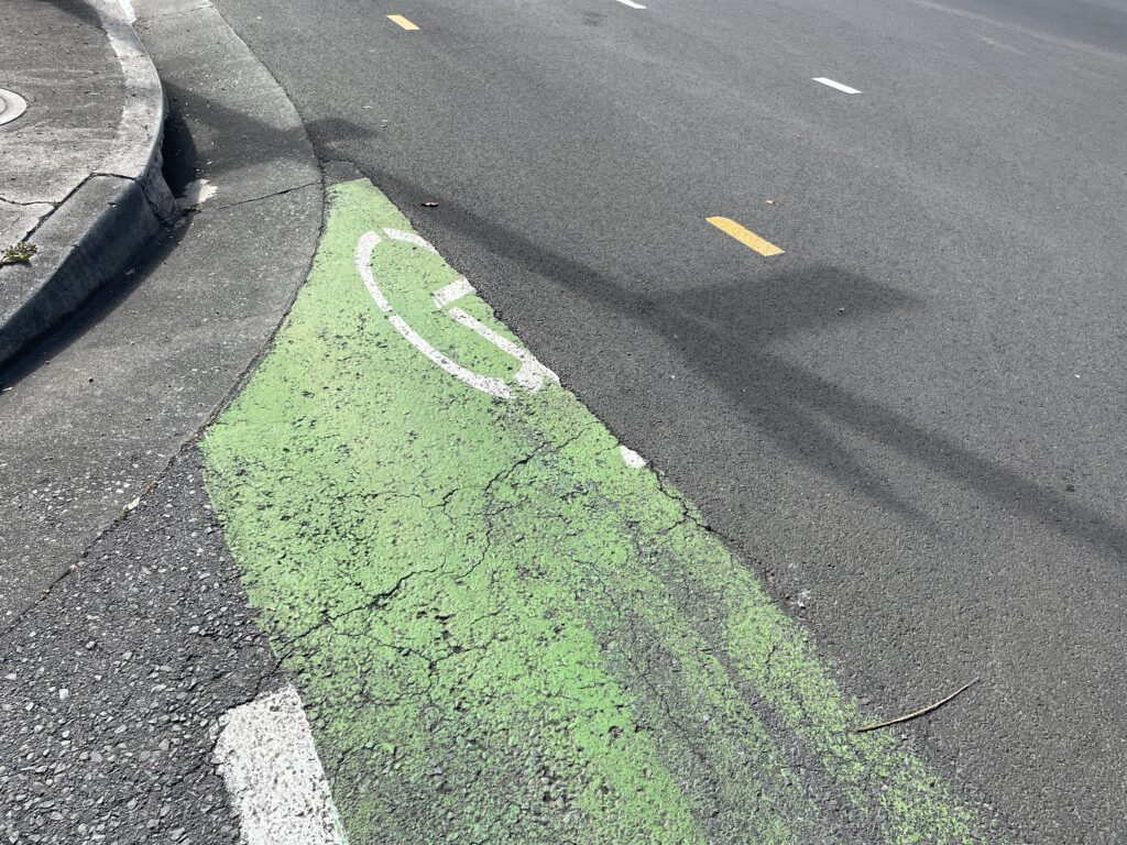 Black road paving covers over a remnant of green bike paint.