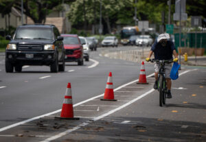 A bicycle rides in the South King Street bike lane next to traffic cones marking the lane April 20, 2026. In the background are white barriers marking the bike lane north of Alapai Street. (Craig Fujii/Civil Beat/2026)