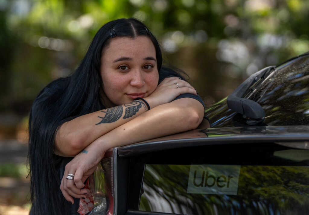 UH pre-med student Peākalika Edwards works as a rideshare driver to make ends meet. She was photographed at Kapiolani Park April 23, 2026. Edwards has noticed that pay from Uber for similar routes and times has decreased. (Craig Fujii/Civil Beat/2026)