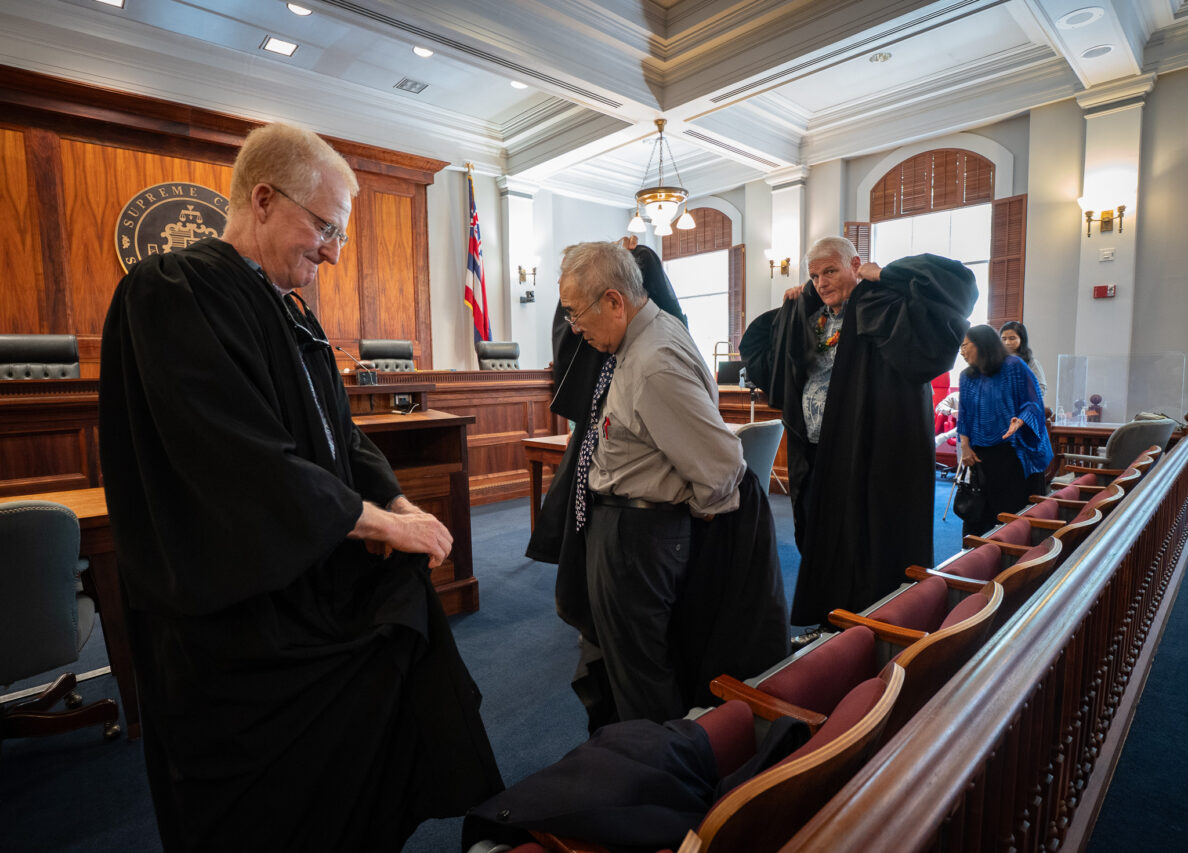Retired judges R. Mark Browning, left, and Paul Murakami don robes before participating in Law Day at Ali'iolani Hale's Supreme Court  courtroom May 1, 2026. Retired Chief Justice Mark Recktenwald is second from left. (Craig Fujii/Civil Beat/2026)