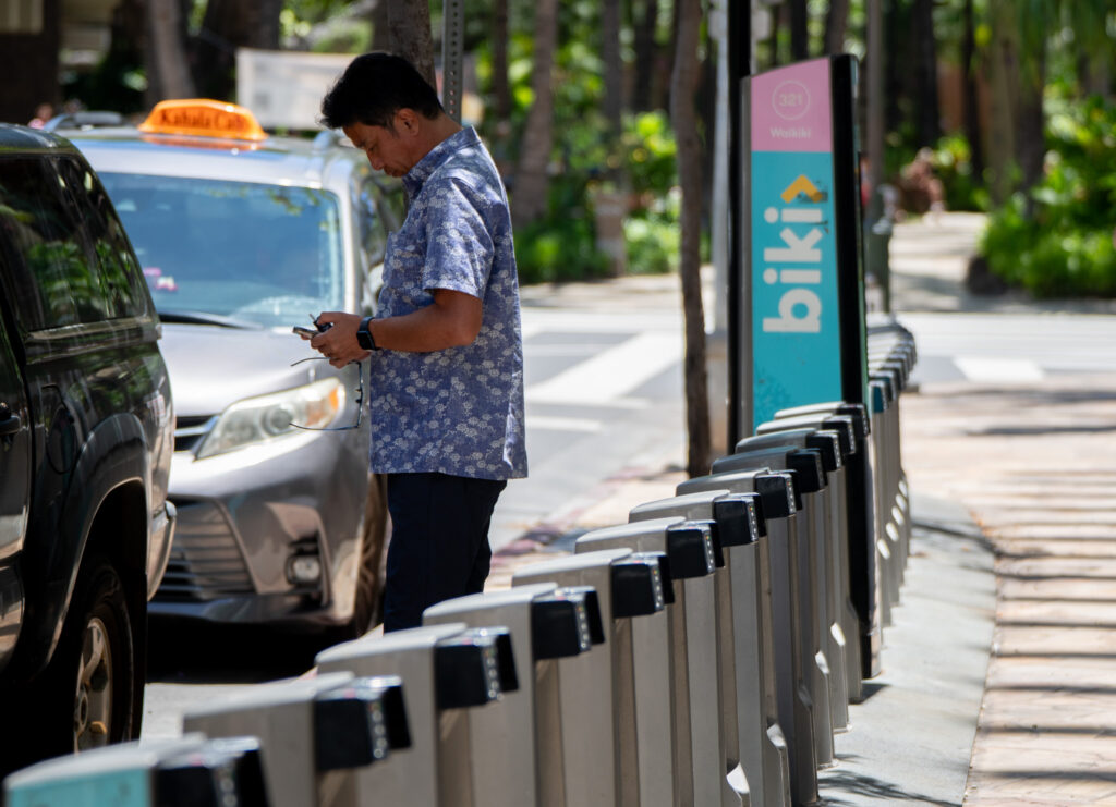 A man stands next to an empty Biki bicycle rack on Seaside Avenue in Waikīkī May 4, 2026. (Craig Fujii/Civil Beat/2026)