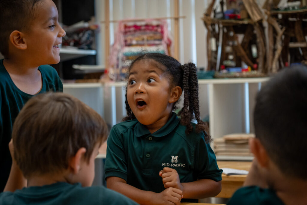 Keilani, 5, has a moment of inspiration during a session with artificial intelligence at Mid-Pacific Institute in Mānoa May 6, 2026. Her classmate Luka, is at left. Noah, back to camera at left, and Knox were also in the class. (Craig Fujii/Civil Beat/2026)