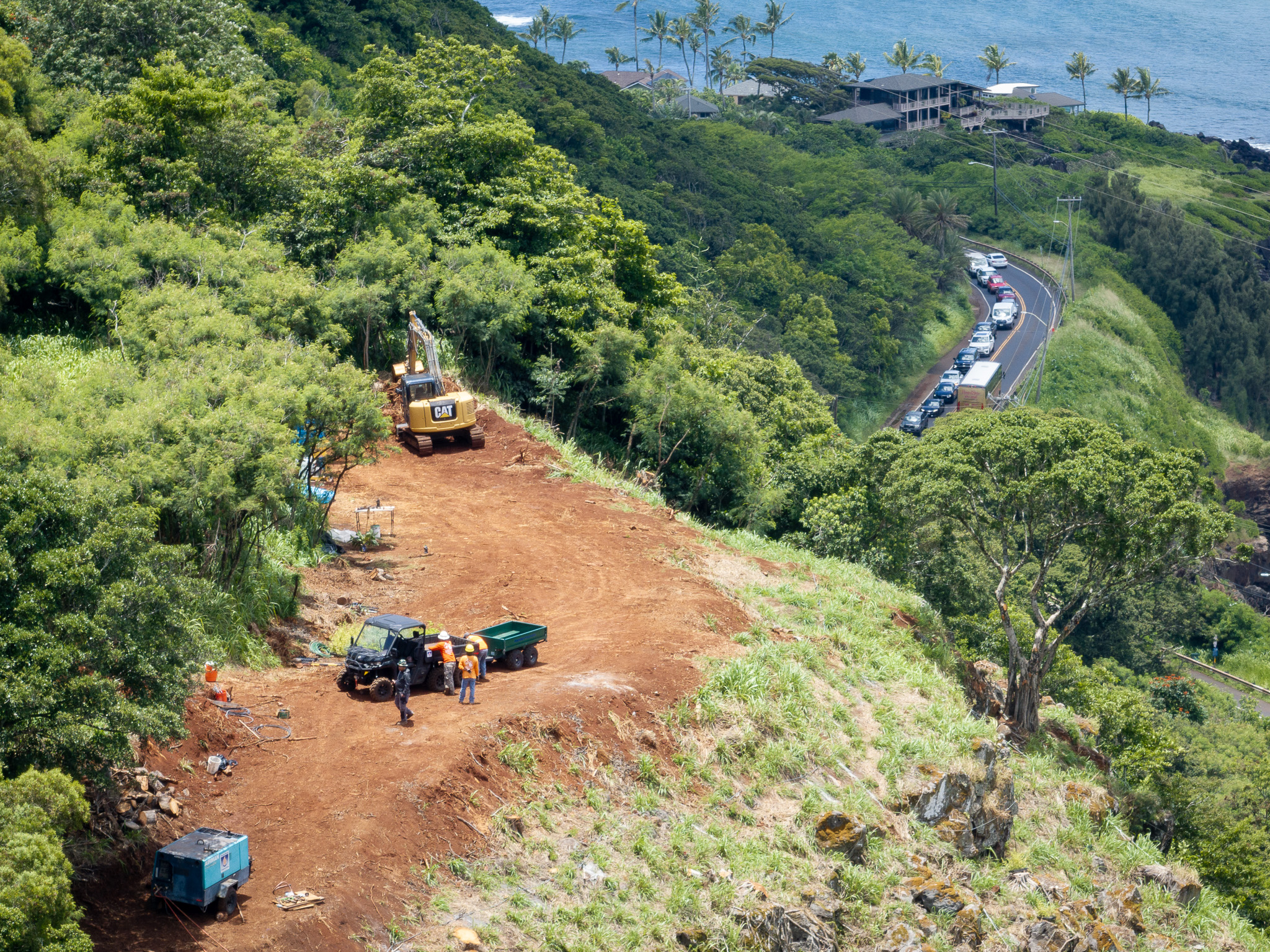 Department of Transportation workers work to stabilize the steep hill adajcent to Waimea Bay May 11, 2026. The Kona low storms in March loosened boulders and rocks which crashed onto the roadway below. (Craig Fujii/Civil Beat/2026)