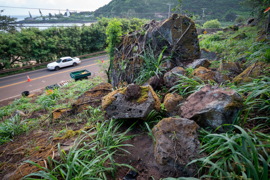 Rocks and a boulder at rest on the lower section of a 230-foot hill next to Kamehameha Highway May 17, 2026. Workers have been shoring up the hillside after boulders crashed onto the road surface April 10. (Craig Fujii/Civil Beat/2026)