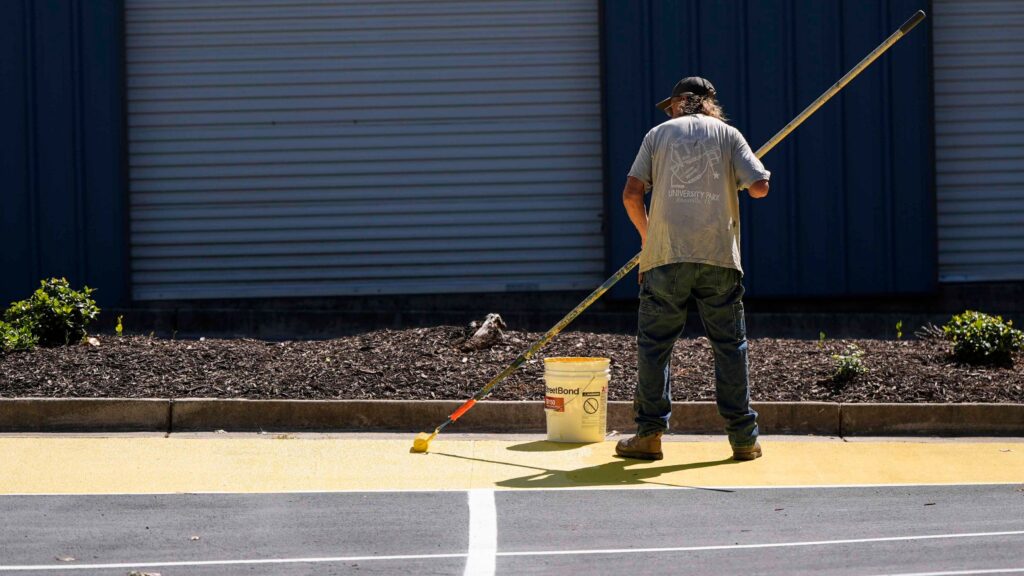 FILE - Ronnie Jefferies paints the parking lot at Science, Arts and Entrepreneurship School to help cool it by making it more reflective, Sept. 4, 2024, in Mableton, Ga. (AP Photo/Mike Stewart, File)