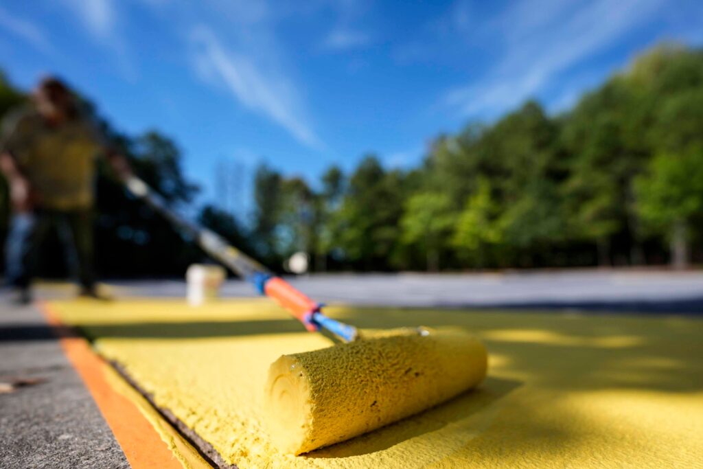 FILE - Ronnie Jefferies paints the parking lot at Science, Arts and Entrepreneurship School to help cool it by making it more reflective, Sept. 4, 2024, in Mableton, Ga. (AP Photo/Mike Stewart, File)