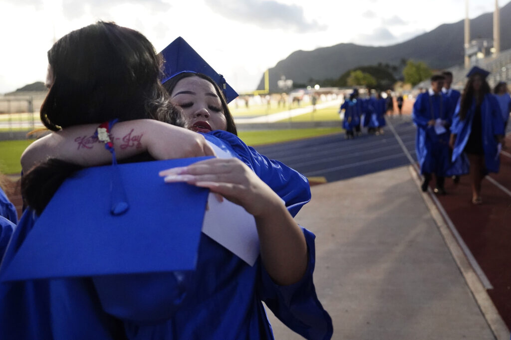 Waiʻanae High School graduate Shaiden Pham hugs a friend after their commencement ceremony Friday, May 22, 2026, in Waiʻanae. (Kevin Fujii/Civil Beat/2026)