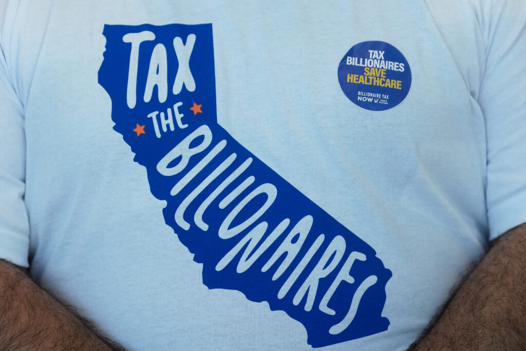 يتم عرض قميص وملصقات للرجال في جناح Billionaires Tax Now خلال مؤتمر ولاية كاليفورنيا الديمقراطية لعام 2026 يوم السبت 21 فبراير 2026 في سان فرانسيسكو. (صورة AP/جيف تشيو)